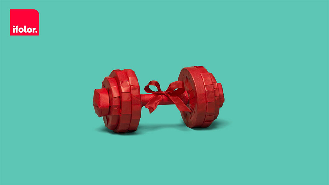 Still of the ifolor film showing dumbbells packed in red wrapping paper on a turqoise background with the ifolor logo in the top left corner.