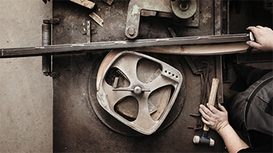 Still of the horgenglarus film showing wood being bendt with a machine by a craftsman to make a classic horgenglarus chair.