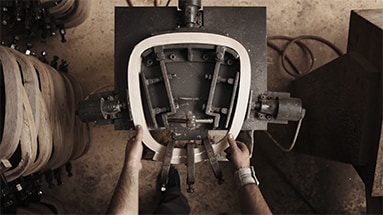 Still of the horgenglarus film showing wood being glued by a craftsman to make the seat of a classic horgenglarus chair.