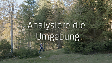 Still of the bkw film showing didier cuche walking through the forest with a white text overlay saying "Analysiere die Umgebung".