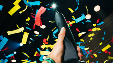 Person holding an edi award in the hand with colourful paper confetti falling from the ceiling.